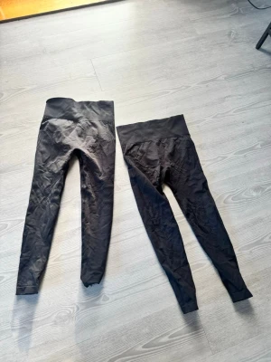 Svarta sömlösa leggings med hög midja - Två par svarta leggings med hög midja och sömlös design. Stretchigt material som formar sig efter kroppen och ger en snygg siluett. Perfekta för träning eller chill. Bred linning för extra komfort och stöd.