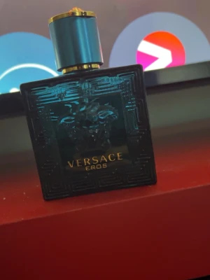Versace Eros EDT   - Versace Eros parfym i en snygg turkos glasflaska 50 ml 25-30 ml kvar med guldtext och Medusa-huvud i relief på framsidan. Flaskan har en lyxig känsla med geometriskt mönster och ett matchande turkost lock med gulddetaljer. Perfekt för dig som gillar exklusiva dofter.