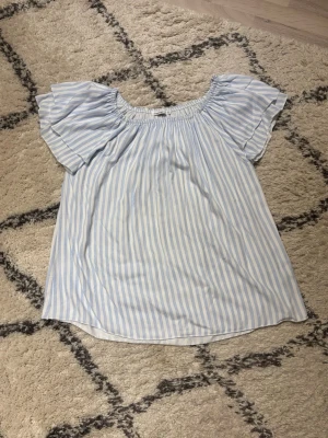 Blåvit offshoulder blus Copenhagen Luxe - Söt blus från Copenhagen Luxe i blåvitrandigt med offshoulder-modell och korta, vida ärmar. Blusen har resår upptill och är gjord i ett lätt, luftigt tyg. Klassisk och fräsch look med vertikala ränder.🤍