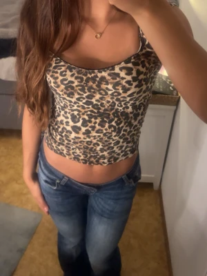 Leopardmönstrad croppad topp - Säljer en croppad topp med leopardmönster. Toppen har smala axelband och är figurnära med en rundad urringning. Materialet känns mjukt och stretchigt, perfekt för dig som vill ha en trendig och bekväm look.