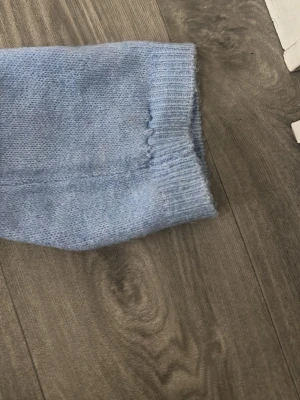 Ljusblå stickad tröja - Mysig ljusblå stickad tröja med rund halsringning och långa ärmar. Tröjan har ribbade muddar vid ärmslut och nederkant. Perfekt för lager på lager och enkel att matcha med jeans eller kjol.
