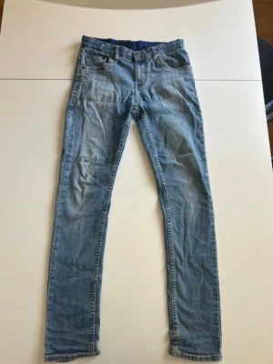 Levi’s Jeans - Säljer ett par ljusblå skinny jeans med klassisk femficksdesign och normal midja. Jeansen har dragkedjegylf och raka benslut. Perfekta för dig som gillar en smal passform och tidlös denimstil. Modellen är 512 Slim Taper. Hör av dig om du har några frågor!