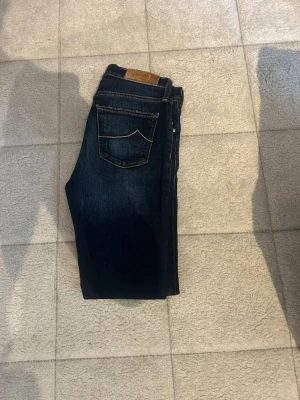 Jacob Cohen jeans  - Snygga mörkblå jeans med klassisk femficksdesign och kontrastsömmar. Jeansen har en rak passform och är tillverkade i ett slitstarkt denimtyg. Perfekta för en avslappnad och trendig look.