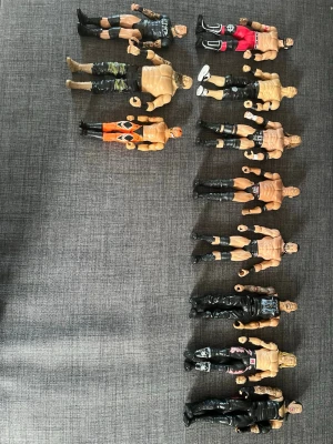 Samling wrestling actionfigurer - Säljer en samling med 11 wrestling actionfigurer i plast. Figurerna har olika utseenden, kläder och poser, bland annat svarta, röda, orange och kamouflagefärgade byxor. Några har tryck på byxorna och detaljerade muskler. Perfekt för dig som gillar wrestling eller samlar på figurer.