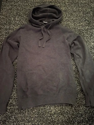 Stickad hoodie - En stilren mörkgrå stickad hoodie med huva. Perfekt för en avslappnad look och enkel att matcha med andra plagg.