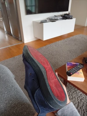 Mörkblå sneakers Louboutin  - Säljer ett par mörkblå sneakers i mocka med matchande blå skosnören och en unik röd yttersula. Skon har en låg profil och klassisk design som passar till många olika stilar. Perfekt för dig som gillar stilrena och bekväma sneakers.