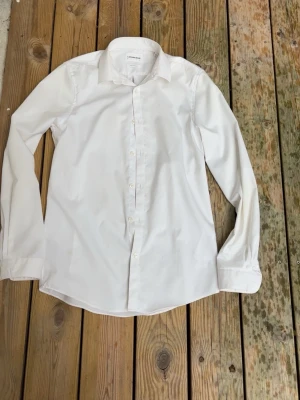 Vit Lindbergh skjorta - Snygg vit skjorta i bomull med lång ärm och klassisk krage. Skjortan har knäppning framtill och enkel, stilren design som passar till många olika looks. Perfekt för dig som gillar en clean och tidlös stil.