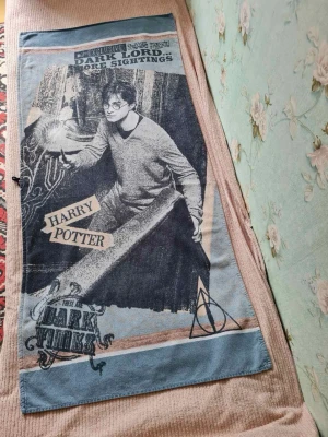 Harry Potter badhandduk med motiv - Harry Potter badhandduk / handduk med stort tryck fram.  Harry Potter-badhandduk 150 × 70 cm – högkvalitativ frotté Material: 100 % bomull. Till salu: en högkvalitativ badhandduk i frotté med Harry Potter-motiv, storlek 150 × 70 cm. Den är mjuk, har god uppsugningsförmåga och passar utmärkt att använda efter badet, vid poolen eller på stranden. Motiv: Harry Potter Mått: 150 × 70 cm Material: Högkvalitativ frotté Mjuk, absorberande och skön att använda Skick: Se bilder