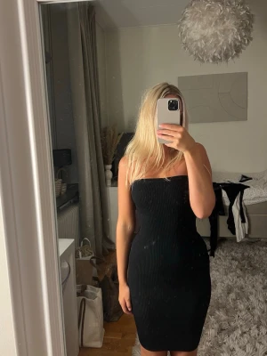 Svart ribbad axelbandslös klänning - Säljer en svart, ribbad och figurnära axelbandslös mini klänning. Storlek 34. Från Nakd