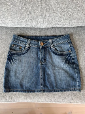 Såå snygg jeanskjol - Så snygg lågmidjad jeanskjol med coola broderi detaljer! Midjemått: 36 längd: 30