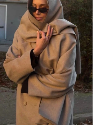 Beige ullkappa med sjalkrage - Säljer en beige kappa med stor sjalkrage och knytskärp i midjan. Kappan har långa ärmar, dolda knappar framtill och en elegant. Perfekt för dig som vill ha en mysig look i höst och vinter.