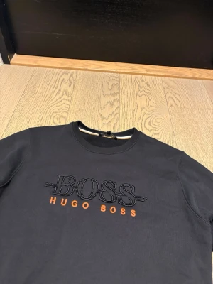 Svart tröja från Hugo Boss - Hugo boss sweater med den klassiska logotypen BOSS. Pris kan diskuteras! ⭐️ Skick: 8/10 🎲 Storlek: S 🎨 Färg: Svart med orange logotyp 📦 Snabb och noggrann leverans