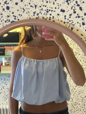 Söt Ljusblå croppad linnetopp - Säljer en ljusblå croppad linnetopp med tunna axelband och luftig passform. Toppen har en enkel och stilren design som passar perfekt till sommaren. Materialet känns lätt och bekvämt mot huden.