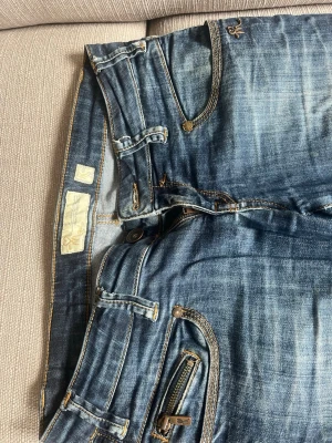 Mörkblå skinny jeans med dragkedja - Snygga mörkblå skinny jeans med dragkedjedetalj på fickan. Jeansen har klassisk femficksmodell, kontrastsömmar och låg midja. Tillverkade i denim med stretch för skön passform 💗W28 L32
