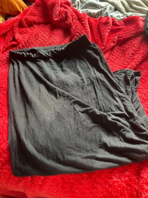 Svart lång kjol med resårmidja - Enkel och stilren svart långkjol med resår i midjan. Kjolen är gjord i ett mjukt och stretchigt tyg som ger en avslappnad look. Perfekt att matcha med en crop top eller hoodie för en chill vibe.