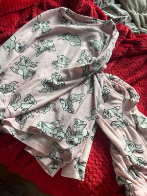 Rosa pyjamas med kaninmotiv - Mysig rosa pyjamas med långärmad tröja och byxor, täckt av gulliga kaninmotiv i svartvitt. Perfekt för chilliga kvällar eller lata morgnar. Materialet känns mjukt och bekvämt mot huden. Söt och lekfull design som passar dig som gillar söta detaljer.