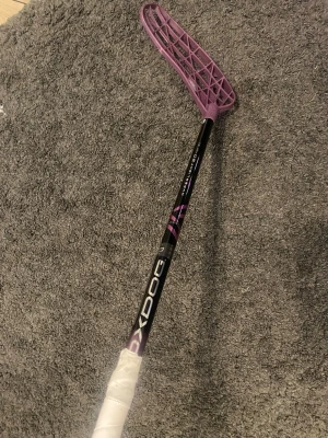 Helt Oanvänd inköpspris 1400 kr !!  31 flex 92 cm  - Säljer en innebandyklubba med svart skaft och vitt grepp. Bladet är lila och har ett coolt mönster. Perfekt för dig som vill sticka ut på planen och ha bra kontroll på bollen.