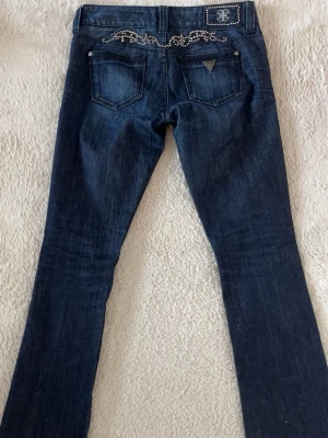 Vintage guess jeans - Lågmidjade boitcut jeans från guess med snygga silver detaljer i mycket bra skick! Midjemått-39cm innerbenslängd-82cm