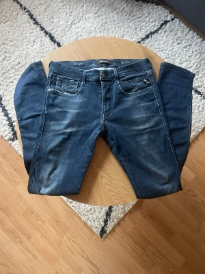 Mörkblå Replay hyperflex  - Tjena👋 Säljer dessa nygga mörkblå jeans i slim fit-modell med diskreta slitningar och kontrastsömmar i storlek W33 L34🤩 Jeansen har en modern tvätt och passar perfekt till en avslappnad stil🧼 Materialet är mjukt denim med hyperflex för extra komfort😮‍💨 Meddela vid frågor!📩