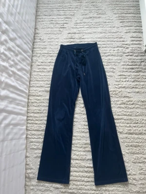 Mörkblå mjukisbyxor med dragsko - Mörkblå mjukisbyxor med raka ben och resår i midjan. Byxorna har dragsko för justerbar passform och en avslappnad look. Perfekta för chill dagar hemma eller när du vill vara bekväm.