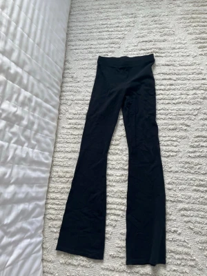Svarta bootcut leggings - Säljer ett par svarta leggings med bootcut-modell och hög midja. De är stretchiga och sitter tajt över låren men har utsvängda ben. Perfekta till sneakers eller chunky boots.