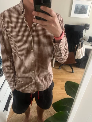 Brun och vit rutig skjorta J.Crew - Säljer en brun och vit rutig skjorta från J.Crew i slim fit. Skjortan är tillverkad i bomull med stretch och har klassisk krage, långa ärmar och knäppning framtill. Perfekt för dig som gillar en clean och tidlös look.