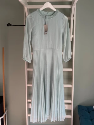 Afton klänning stl: EU 34 - Midi lång klänning från hobbs london i nyskick. Aldrig använd med lapparna kvar i storlek xs/eu:34. Ser lite grå ut på bilderna men den är sage green i verkligheten. Ordinare pris: 2595kr 