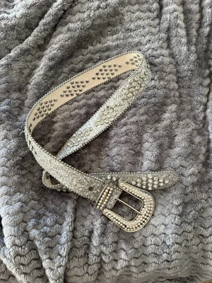 Glittrigt silverfärgat bälte fest - Snyggt bälte i silver med massor av glittrande stenar och detaljer. Har bara använt en gång till en fest Passar till jeans eller kjol för en cool och trendig look.
