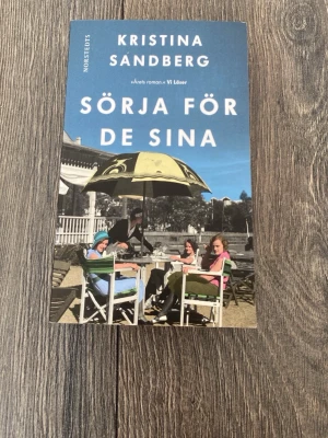 Sörja för de sina av Kristina Sandberg - Romanen 'Sörja för de sina' av Kristina Sandberg är en pocketbok med blått omslag. Boken handlar om Majs liv som hemmafru i 1940- och 50-talets Sverige och skildrar vardag, klass och familjeliv. Utgiven av Norstedts.