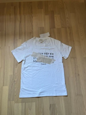 Vit t-shirt Maison Margiela Paris - Maison Margiela T-shirt – helt ny med tags  Säljer en Maison Margiela T-shirt i helt nytt skick, med tags kvar. Stilren vit modell med klassisk Maison Margiela-design.  * Skick: Ny * Tags: Kvar * Färg: Vit * Storlek: M passar dig som är mellan 170 ungefär upp till 180 cm lång. Är 174 cm lång på bilden 🙌🏼 * Äkta vara  Säljes då den inte kommer till användning. Hör av dig vid intresse!
