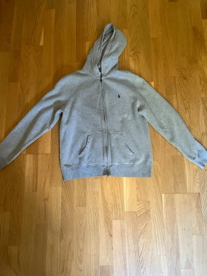 Grå zip hoodie från Ralph Lauren - Säljer eb grå zip hoodie Ralph Lauren med en mörkblå häst. Äkta! 