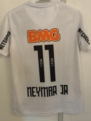 Vit Santos Neymar Jr matchtröja - Säljer en vit Santos matchtröja från Nike med Neymar Jr och nummer 11 på ryggen. Tröjan har tryckta sponsorer som BMG och Netshoes, samt Santos klubbmärke på bröstet. Tillverkad i Dri-FIT material som andas och har korta ärmar. Mycket populär och trendig tröja. Sitter rikitigt bra på armarna och är bra kvalité 