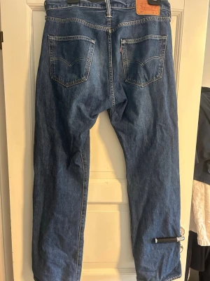Blåa Levis 501 Jeans - Säljer ett par Levi’s 501 jeans Original Fit med Warp Stretch i storleken 34/32 och i färgen/tvätten Subway Station. Perfekta jeans för de som söker efter en mer avslappnad och bred stil. Byxorna är i väldigt bra skick och har inga defekter. Pris kan diskuteras vid snabb affär.