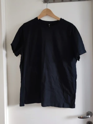 Svart basic t-shirt från Xint - En svart basic t-shirt från Xint i storlek XL. Klassisk rund halsringning och korta ärmar. Tillverkad i mjuk bomull som känns skön mot huden. Perfekt till jeans eller shorts för en clean och enkel look.