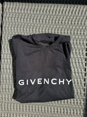 Svart Givenchy t-shirt med logga - Snygg svart t-shirt från Givenchy med stor vit logga framtill. Klassisk rund halsringning och mjukt bomullsmaterial som känns skönt mot huden. Perfekt för dig som gillar stilrena designer och exklusiva märken. Nypris ligger på ca 4000kr