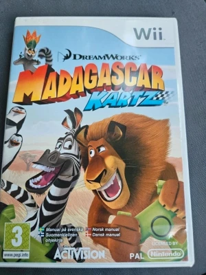Madagascar Kartz till Nintendo Wii - Madagascar Kartz är ett racingspel till Nintendo Wii där du kan spela som karaktärer från DreamWorks Madagascar-filmerna. Omslaget är färgglatt med figurer som lejonet Alex och zebran Marty. Spelet levereras i ett plastfodral med manual på flera språk.