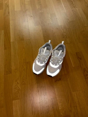 Beige och vita chunky sneakers - Säljer ett par chunky sneakers i beige och vitt med meshpaneler och detaljer i syntetmaterial. Skorna har en tjock sula i svart och vitt samt snörning framtill. Perfekta för dig som gillar en sportig och trendig look.