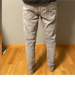 Ljusgrå raka jeans - Säljer ett par ljusgrå jeans med rak passform och klassiska fem fickor. Jeansen har en enkel design utan synliga loggor och är tillverkade i ett mjukt denimtyg. Perfekta för dig som gillar en clean och avslappnad stil.