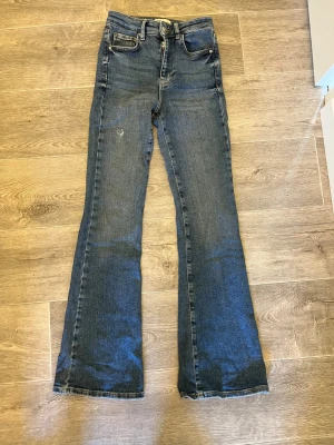 Blå bootcut jeans  - Ett par klassiska blå bootcut jeans från Gina tricot med fem fickor och dragkedja. Jeansen har ett litet hål slitning som ger en extra stilren detalj. Tillverkade i denim med lätt stretch för skön passform och dom är använda några få gånger. Medelhögmidja. Lite korta i benen för mig som är runt 170 cm💗