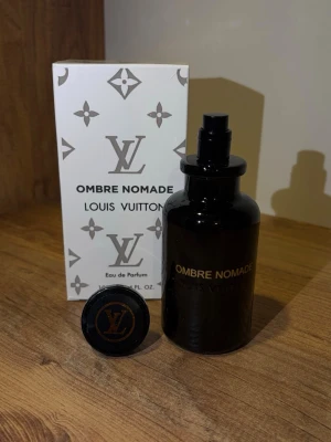 Louis Vuitton Ombre Nomade parfym - Exklusiv parfym, Ombre Nomade, i en elegant svart glasflaska med gulddetaljer. Flaskan rymmer 100 ml och har en stilren, rund form. Medföljer gör originalkartong i vitt med klassiskt LV-mönster och logotyp.