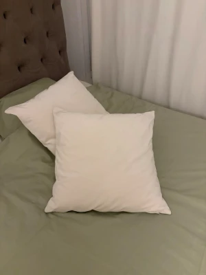 Två vita soffkuddar Hemtex - Säljer två vita fyrkantiga soffkuddar med mjukt tyg. Perfekta att ha i soffan eller sängen för extra komfort. Klassisk design som passar in i de flesta hem och inredningsstilar. Material sammet 