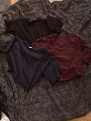 Tre t-shirts i olika färger barn - Säljer ett set med tre t-shirts i svart, marinblå och vinröd. Alla har rund halsringning och korta ärmar. Perfekta att matcha med jeans eller kjol för en avslappnad look.