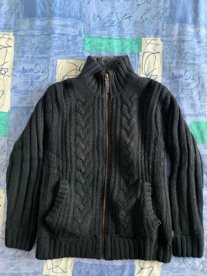 MEN’S CABLE KNIT CARDIGAN/JACKET BY ‘BLEND’ FROM 2009 - HEAVY, FULL-ZIP, KNIT CARDIGAN/JACKET.  GOOD CONDITION. SIZE L. WARM FLEECE-LINED INTERIOR.  FAUX-LEATHER TRIM ALONG THE ZIP. 