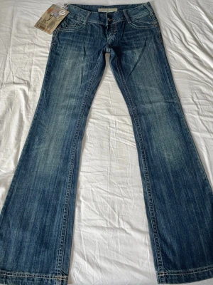 Vintage lågmidjade bootcut jeans  - Jättefina utsvängda jeans med lappar kvar i en fin warmtonad mörkblå med coola slitningar. Strl S // midja 38cm tvärsöver, innerbenslängd 80cm, grenhöjd 18cm 