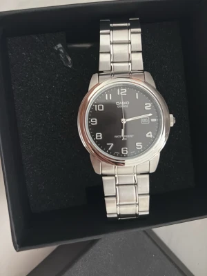 Klassisk silverfärgad Casio klocka - Stilren Casio armbandsklocka i silver med svart urtavla och tydliga vita siffror. Klockan har datumvisning och länkarmband i metall. Perfekt accessoar för dig som gillar enkel och tidlös design. 