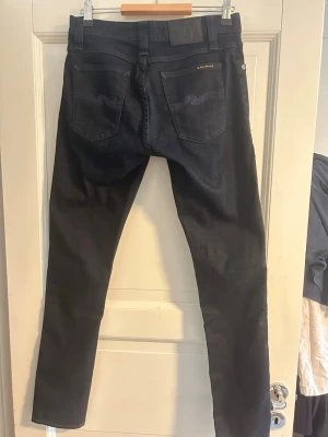 Mörkblåa Nudie jeans - Säljer ett par nudie jeans i storlek 29/30. Modellen är skinny lin och är perfekt för de som söker lite tajtare modeller. Bara använda ett fåtal gånger. De är rätt så mörka i färgen och kan därför se lite svartaktiga ut. Pris kan diskuteras vid snabb affär.