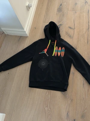 Nike Jordan hoodie - Säljer en svart hoodie från Nike i serien Jordan. Tröjan är en del av en limiterad kollektion och finns inte att köpa i butik, den finns nästan inte ny någonstans. Den är ovanlig. Det är en tröja med luva och snören och med ett unikt och snyggt tryck på baksidan, en jumpman brodering och flera andra Jordan symboler.