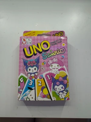 UNO Sanrio kortspel rosa - UNO Sanrio är ett kortspel med gulligt rosa tema och motiv från Sanrio-karaktärer som Kuromi och My Melody. Lådan är färgglad med illustrationer och spelet passar för 2-10 spelare från 7 år. Perfekt för spelkvällar med vänner eller familj. KAN KANSKE saknas fåtal kort sedan ett paket är öppnat, men osäkert eftersom det aldrig använts, bara öppnat.