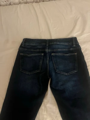 Mörkblå utsvängda jeans - Säljer ett par mörkblå jeans med utsvängda ben och hög midja. Jeansen har två stora fickor fram och bak samt markerade sömmar. Perfekta för dig som gillar retrostil och vill ha ett par riktigt snygga jeans med 70-talsvibbar.