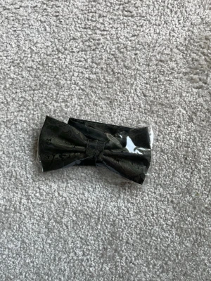 Mörkgrön fluga med diskret mönster - Snygg mörkgrön fluga med subtilt paisleymönster, perfekt för att lyfta din outfit. Flugan är förknuten och har en klassisk form. Materialet ser ut att vara satinliknande tyg som ger en elegant känsla.